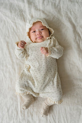 Baby in the Lumiere Classic Blossom Bodysuit being held – highlighting the soft knit texture and charming floral pattern